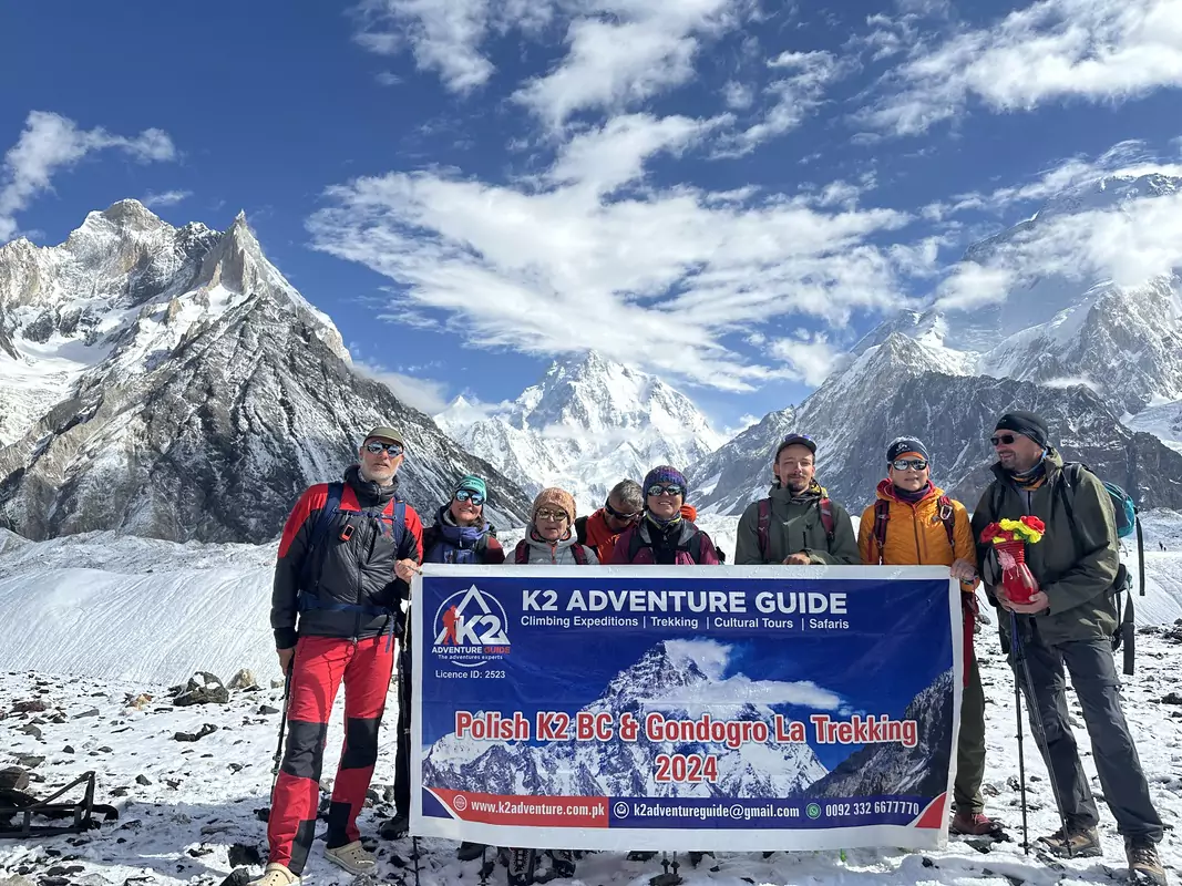 K2 and Gondogoro La Trek Trekkers holding K2 Adventure banner during the K2 and Gondogoro La Trek with snow-covered peaks in the background