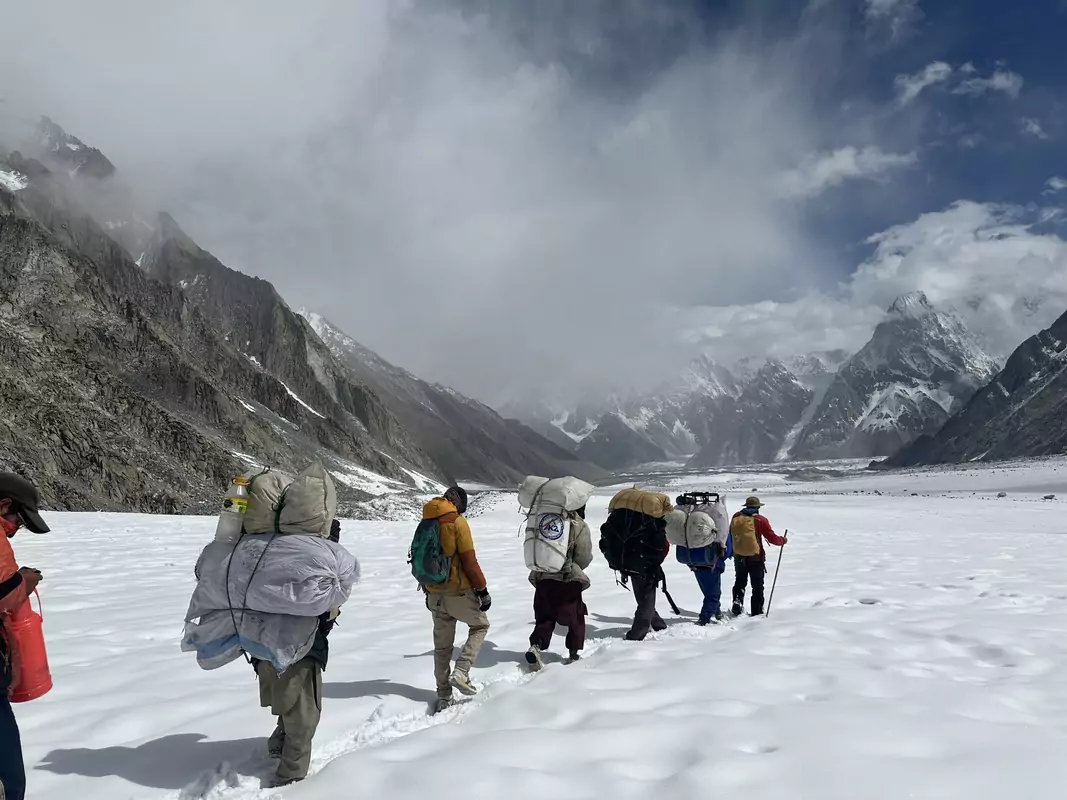 crossing-gondogoro-la-snowy-pass Trekkers crossing the snowy Gondogoro La Pass with stunning mountain views and deep snow underfoot during the K2 trek